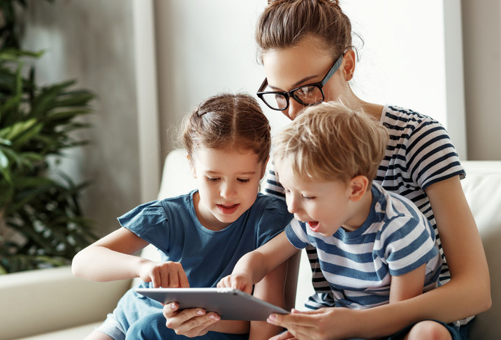 mother helping two kids with iPad